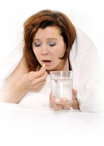 Ung kvinde i sengen med et stort glas vand